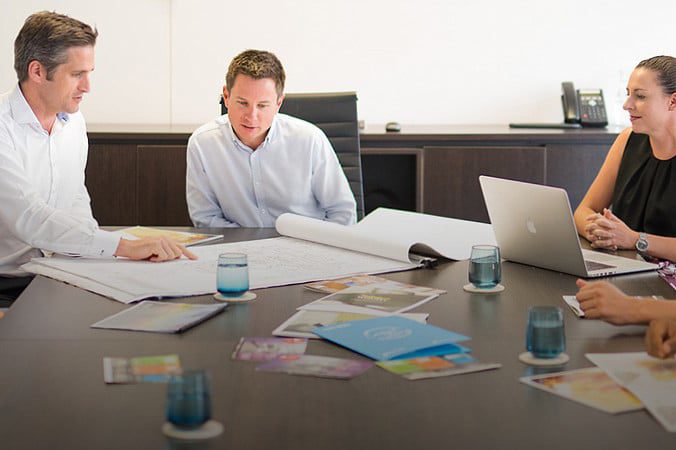 People around meeting table looking at drawings